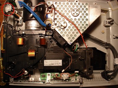 En cours de remontage, la partie noire est le système optique, on aperçoit les nappes de commande des 3 LCD, à droite, l'emplacement de la lampe et de sa ventilation. En haut à gauche le petit cercle rouge montre un bout du capot supérieur encore accroché à sa vis tel un bernique à son rocher !